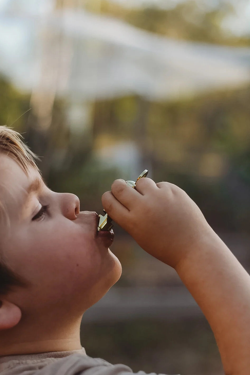 Kid savoring chocolate by the campfire in warm autumn light — cozy outdoor moment after a day of exploring