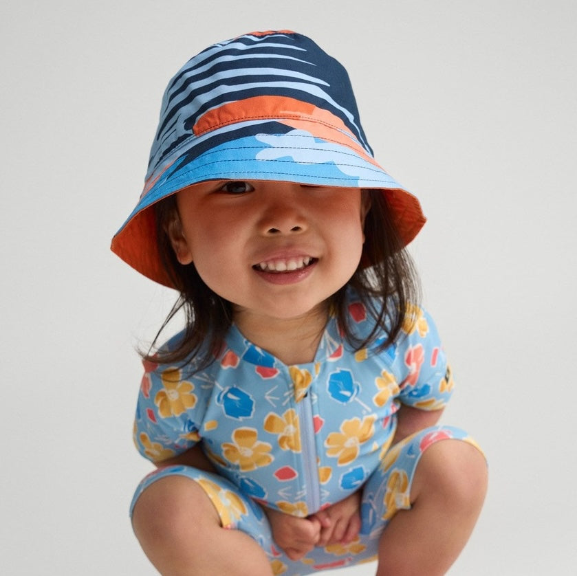 Happy kids building sandcastles together on a sunny beach, wearing protective summer hats and light clothing