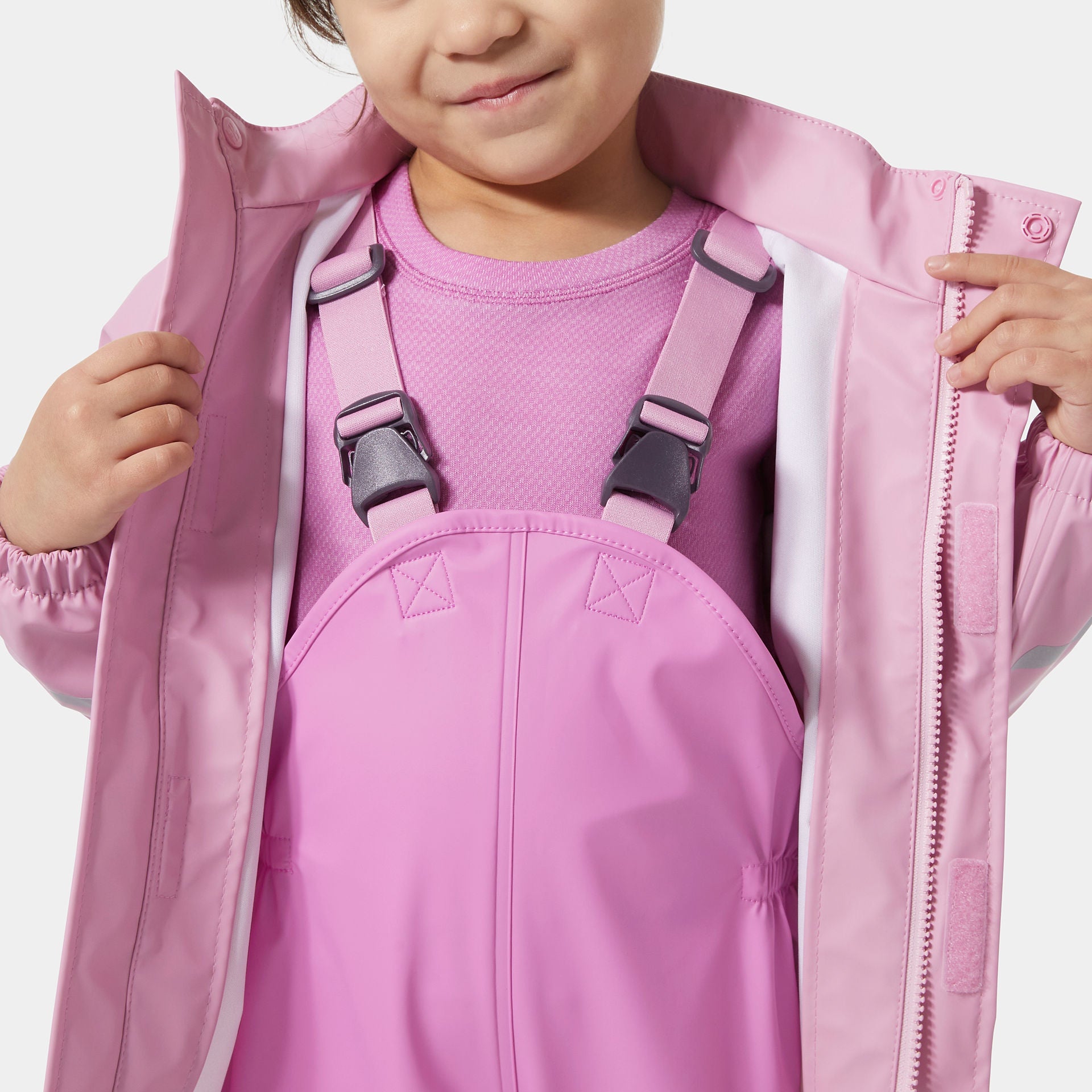 Child wearing a pink jacket and overalls on a white background