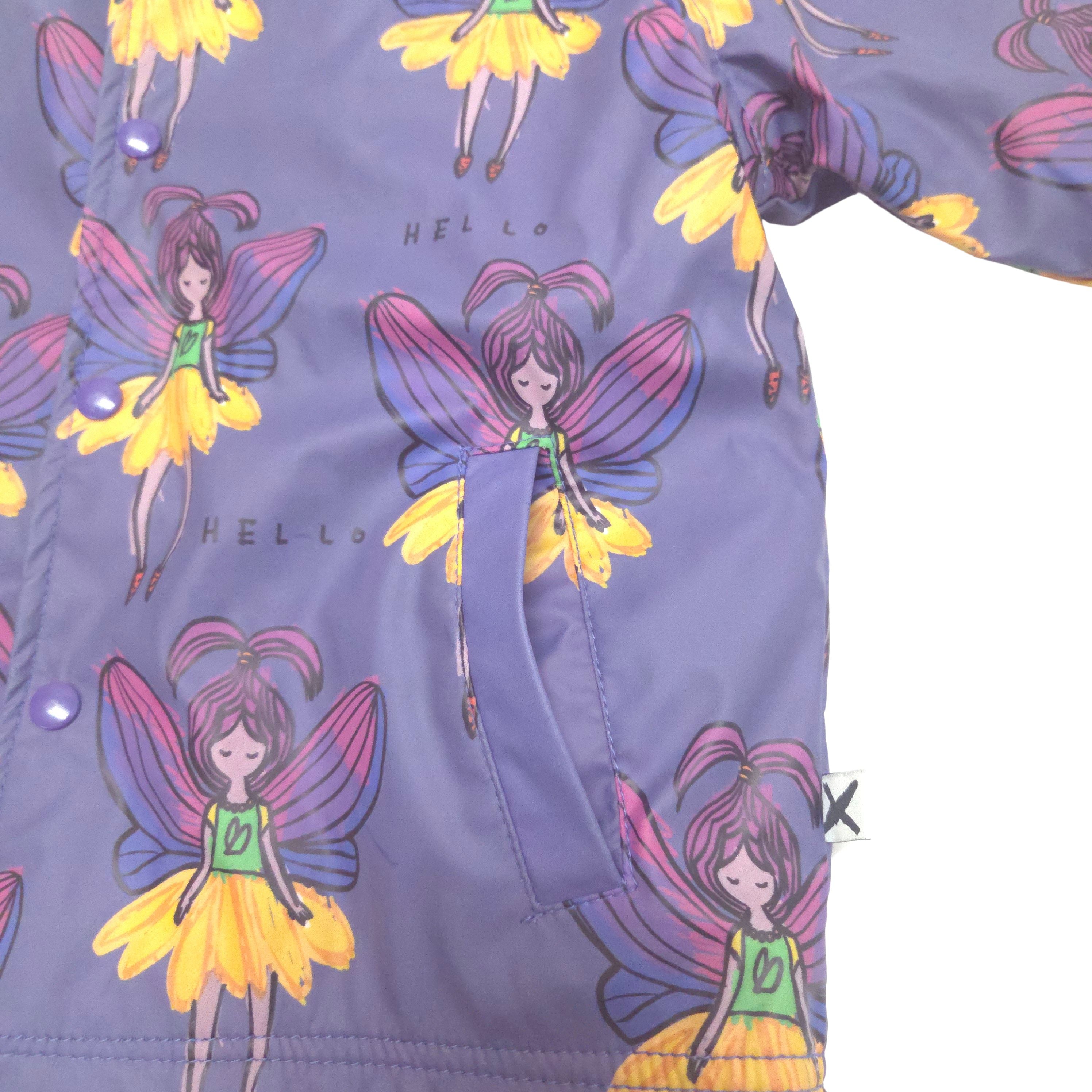 A close-up of a children's purple jacket or raincoat featuring a repeating print of cartoon fairy characters with yellow and pink wings, plus a front pocket.