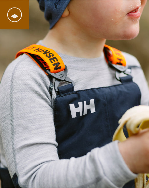 Person wearing a Helly Hansen apron with orange strap, holding a yellow object.