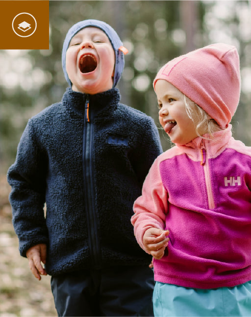Two children in colorful jackets outdoors with a blurred natural background