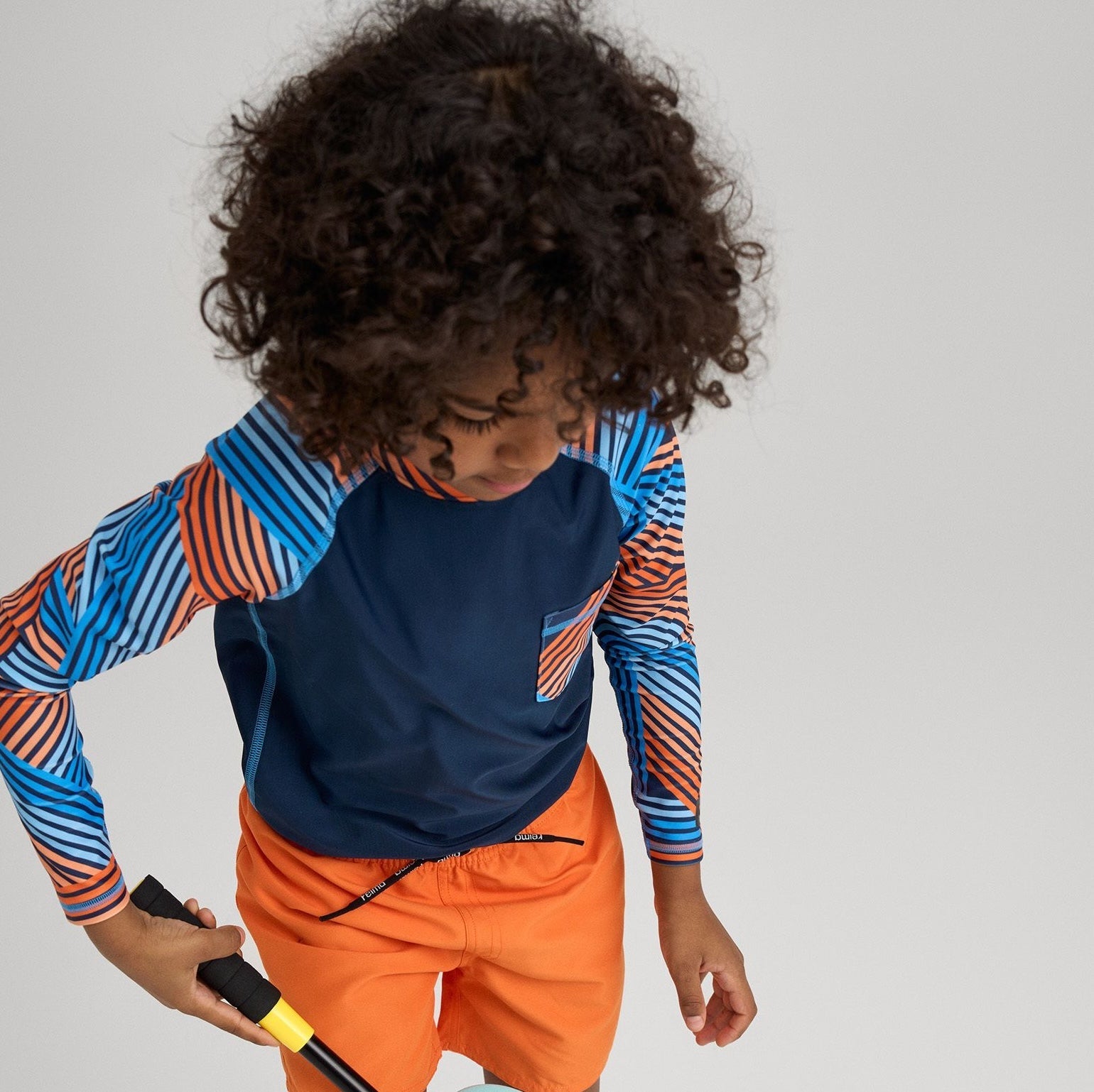 Summer adventure by the water – child in sun-protective swim gear playing with a fishing net
