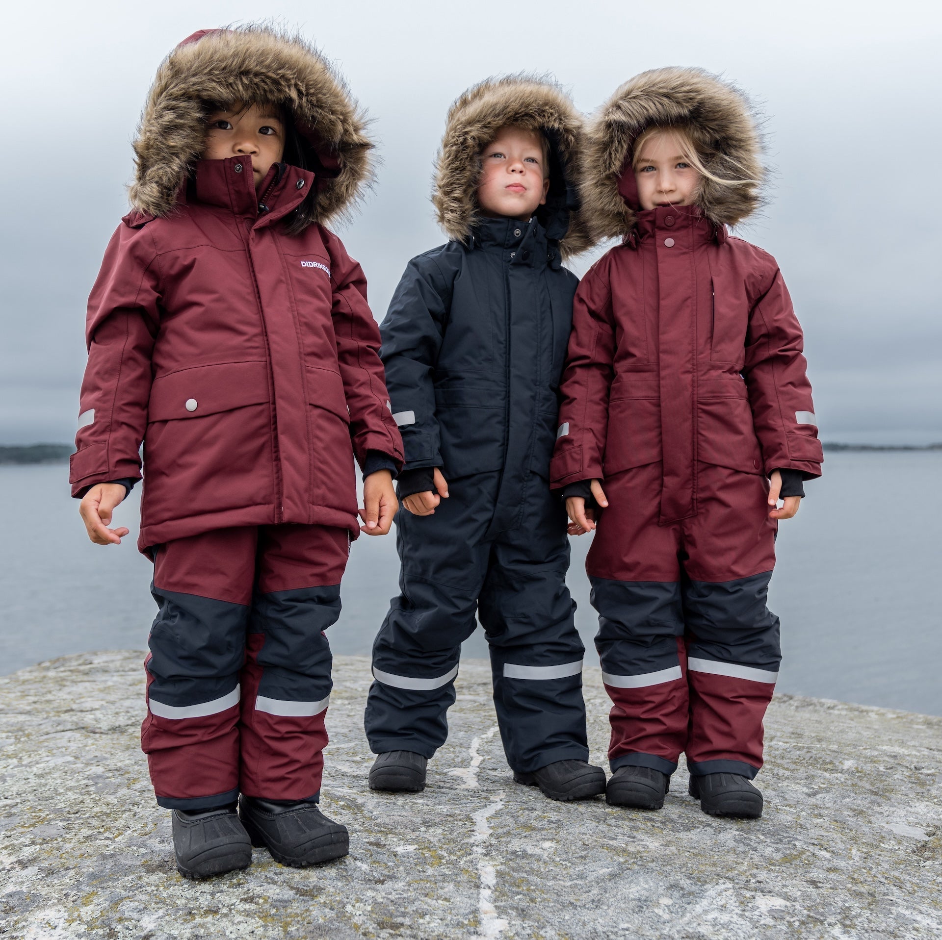 Outdoor winter play — child dressed in blue snow gear sliding through snowy woods