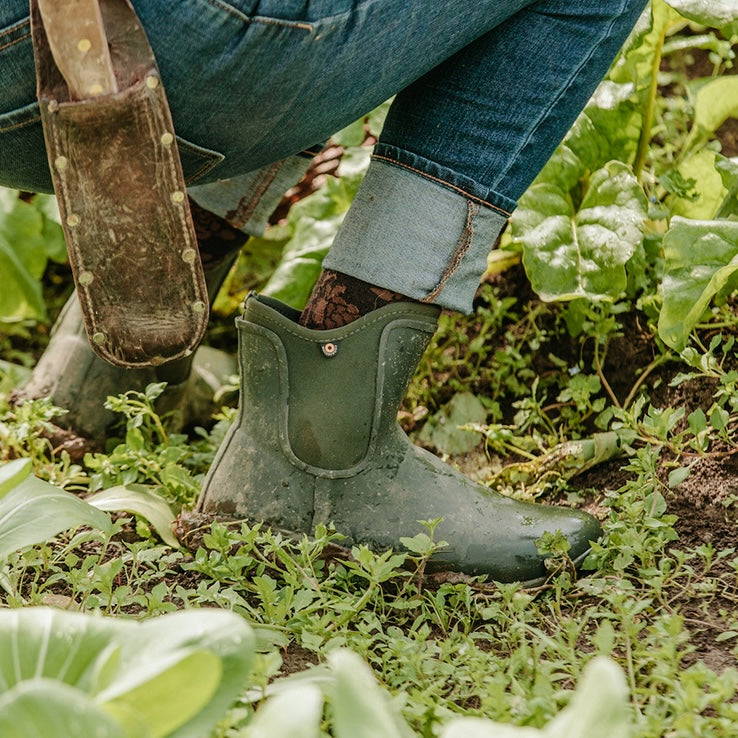 Person wearing waterproof ankle boots on a grassy trail, showcasing durable outdoor footwear for hiking and everyday wear