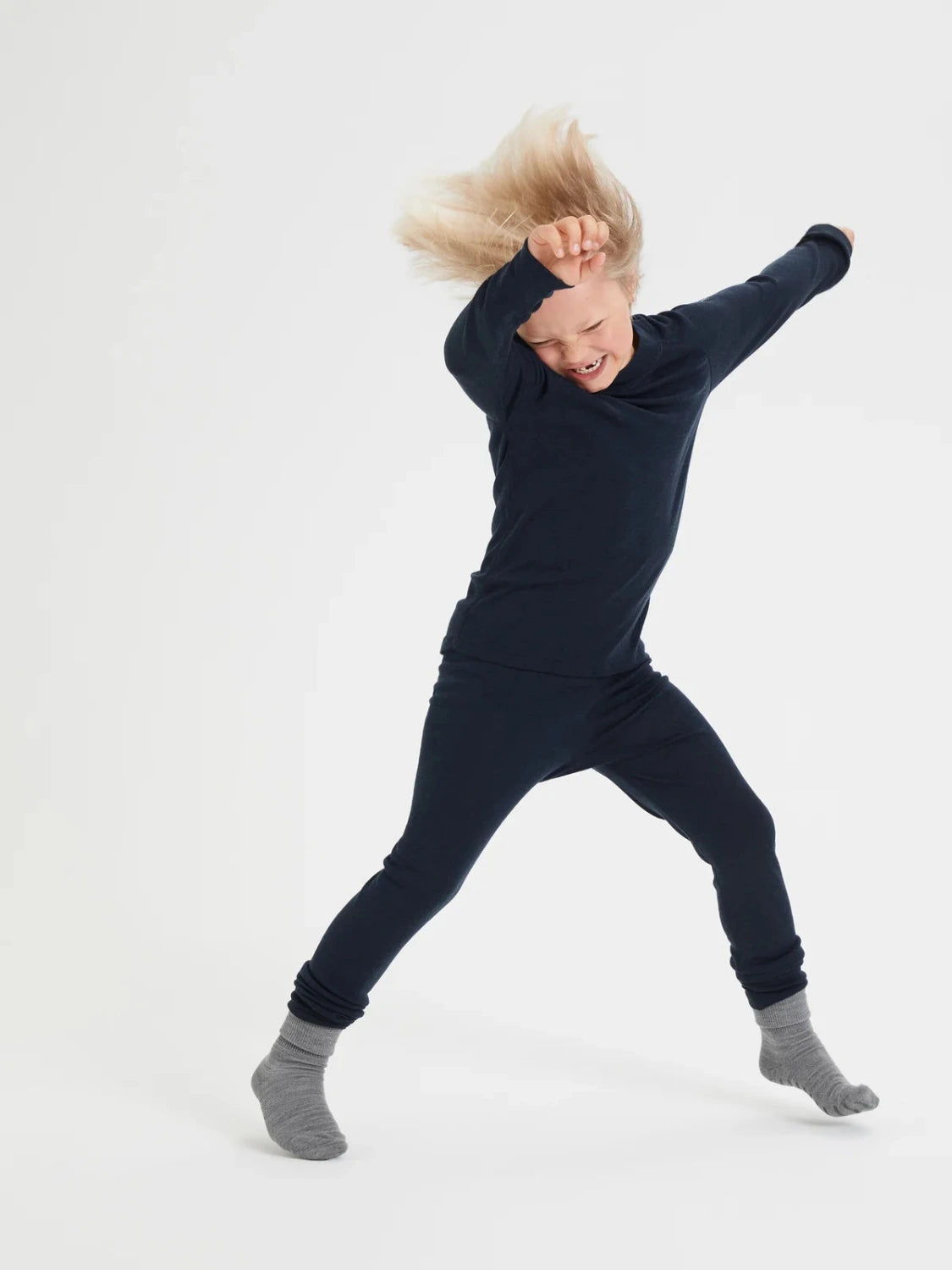 Child wearing a navy blue Merino wool base layers on a white background
