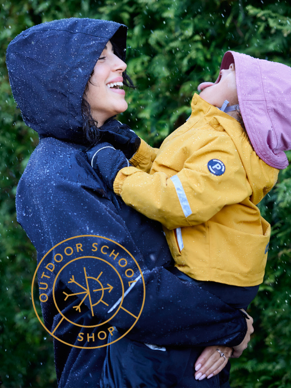 Woman holding a child in a snowy setting with 'Outdoor School Shop' logo.